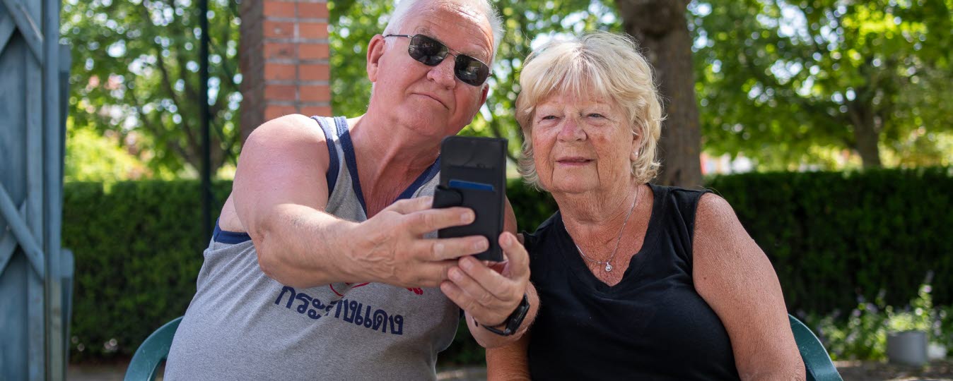 Äldre man och kvinna tar en selfie med en mobiltelefon. 