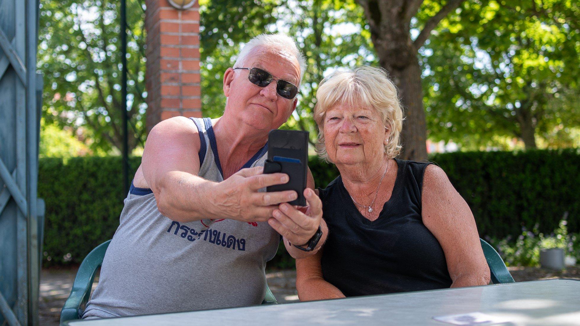 Äldre man och kvinna tar en selfie med en mobiltelefon. 