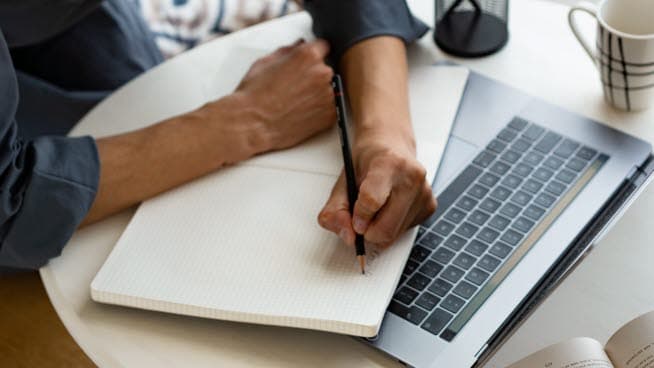 Bild på person som skriver i en anteckningsbok