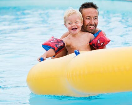 Förälder och barn som leker i pool.