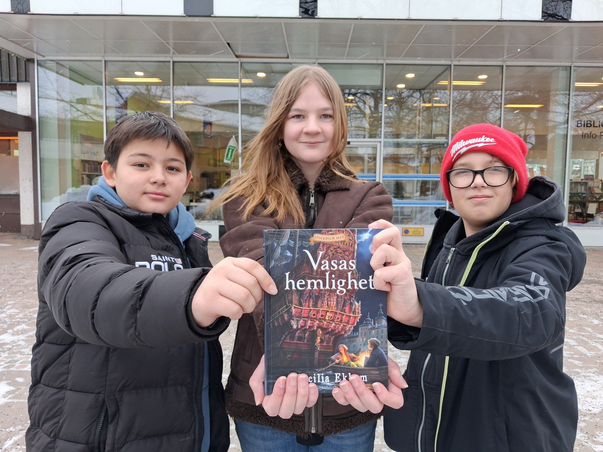 tre barn som h&aring;ller i en bok